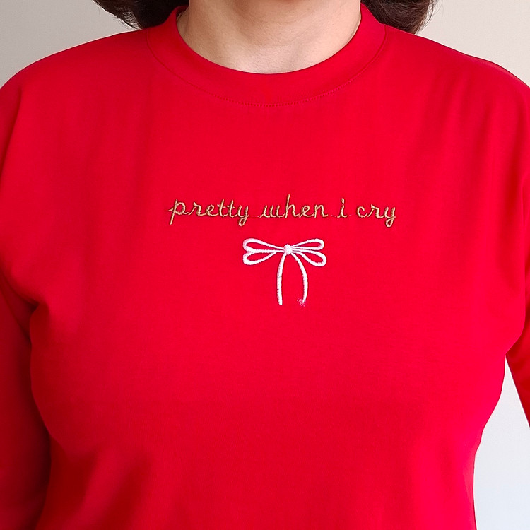 نمای نزدیک گلدوزی نوشته و پاپیون روی تیشرت زنانه قرمز